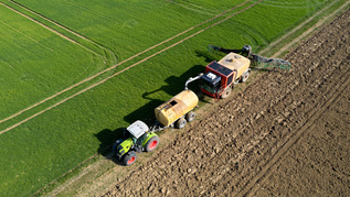 Traktor auf Feld bei Düngung