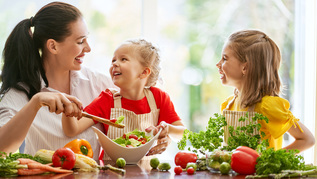 Eine Mutter bereitet mit ihren Kinder zusammen ein Essen zu.