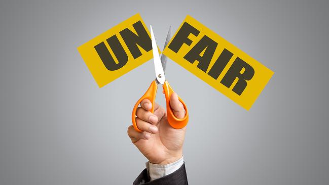 Schere zerschneidet Zettel mit dem Wort Unfair in Un und fair Schere zerschneidet Zettel mit dem Wort Unfair in Un und fair