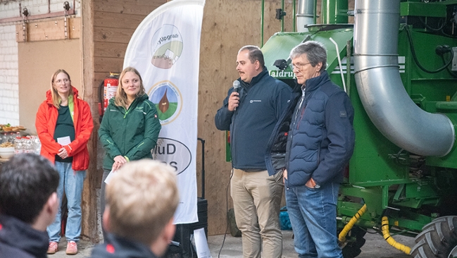 Personengruppe in Scheune vor einem Traktor Personengruppe in Scheune vor einem Traktor