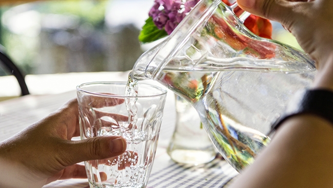 Ein Glas wird mit Wasser gefüllt. Ein Glas wird mit Wasser gefüllt.
