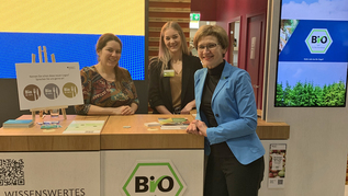 Drei Personen am Messestand (verweist auf: BIOFACH 2024: Bio-Wertschöpfungsketten und Außer-Haus-Verpflegung im Fokus)